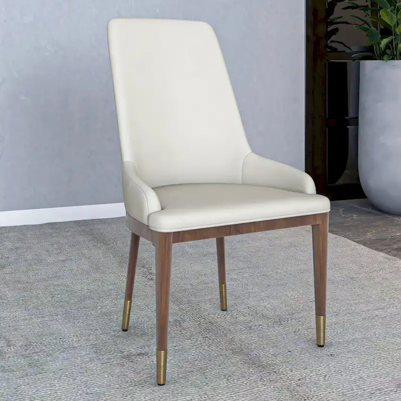 Sedia da pranzo imbottita in pelle con struttura in legno di gomma, schienale alto e gambe con accenti dorati per soggiorno